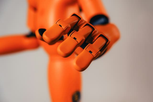 Orange robotic hand typing on a keyboard